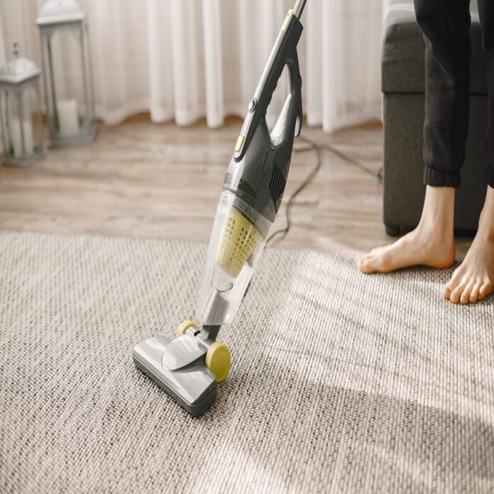 Woman vacuuming mat at home in a good mood